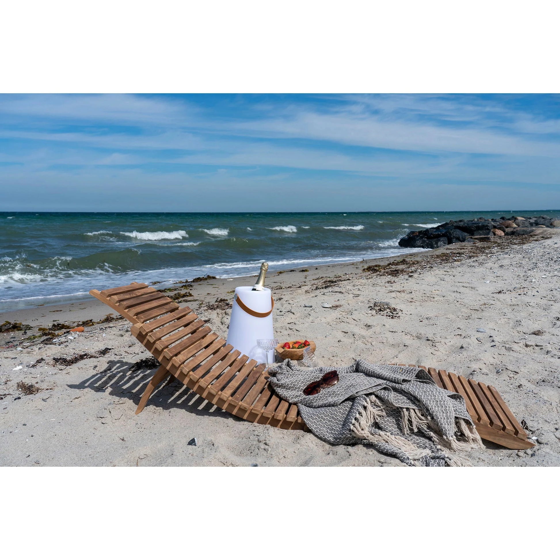 Chaise longue asymétrique en teck sur une plage pour une relaxation élégante