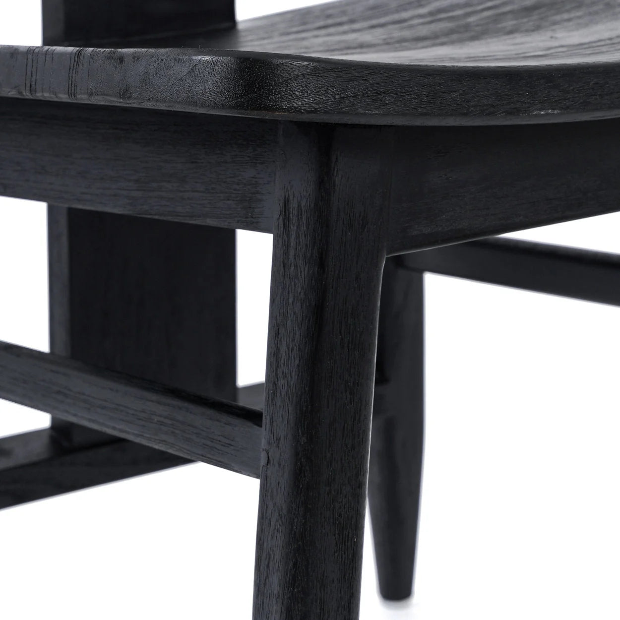Premier plan d’une chaise en teck noir mat avec grain visible dans une salle à manger