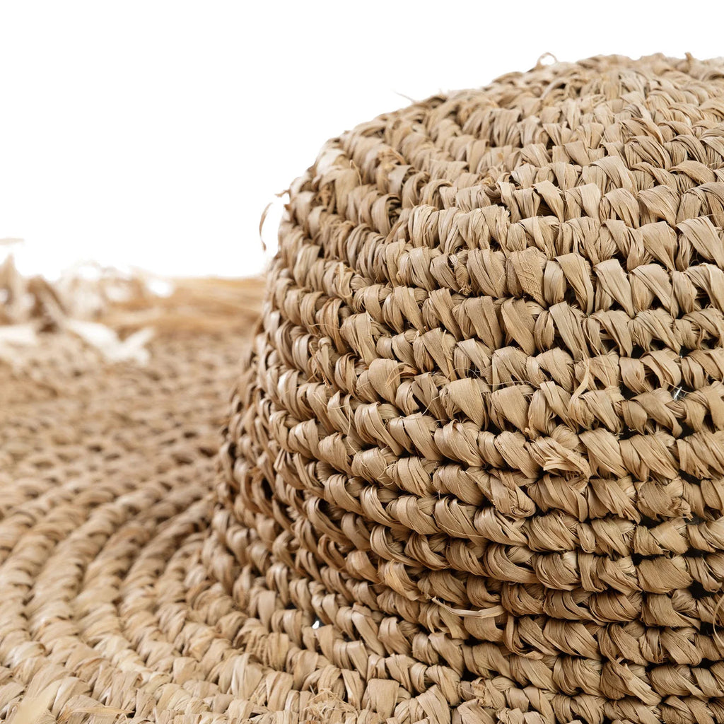 Gros plan sur chapeau large bord en raphia naturel tressé frangé beige