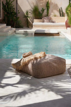 Poufs beige en tissu tissé frangé au bord de piscine