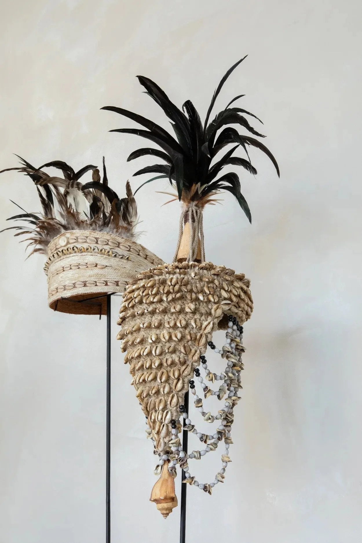 Chapeau décoratif tribal orné de coquillages et plumes sur socle noir naturel