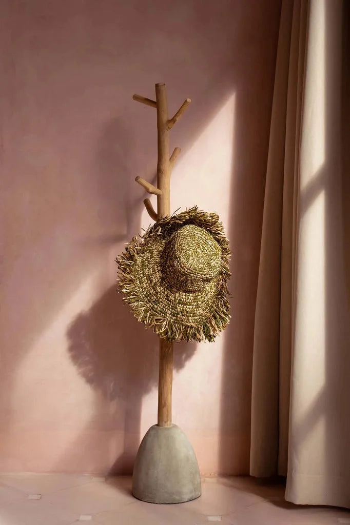 Chapeau en paille sur un portemanteau en béton naturel pour décoration intérieure