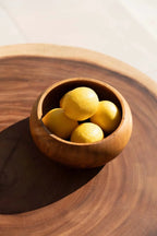 Bol en bois de teck massif rond naturel rempli de citrons jaunes lumineux