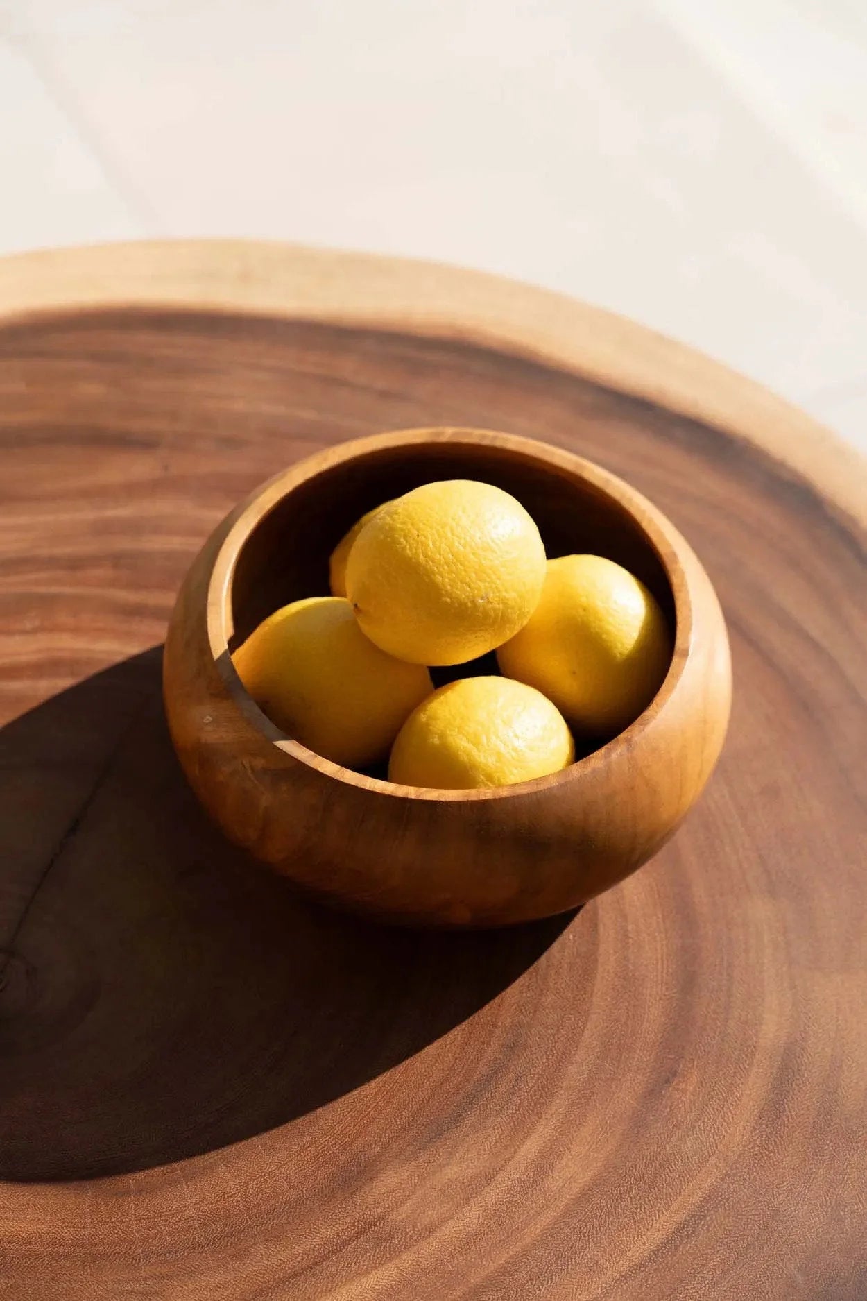 Bol en bois de teck massif rond naturel rempli de citrons jaunes lumineux