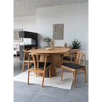 Table de salle à manger en bois clair avec base cylindrique à lattes et chaises noires