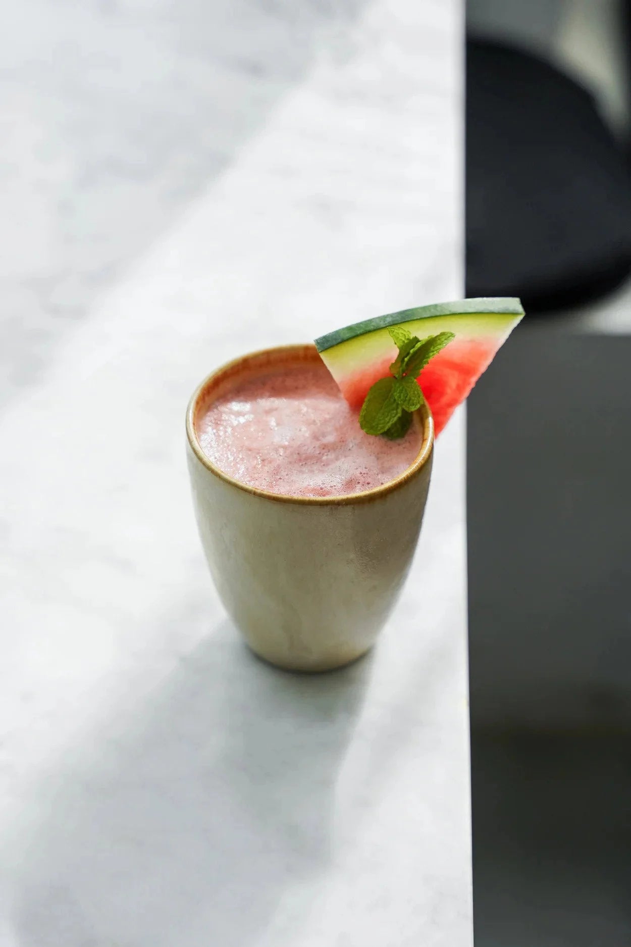 Coupe en céramique artisanale beige avec smoothie pastèque rose et menthe