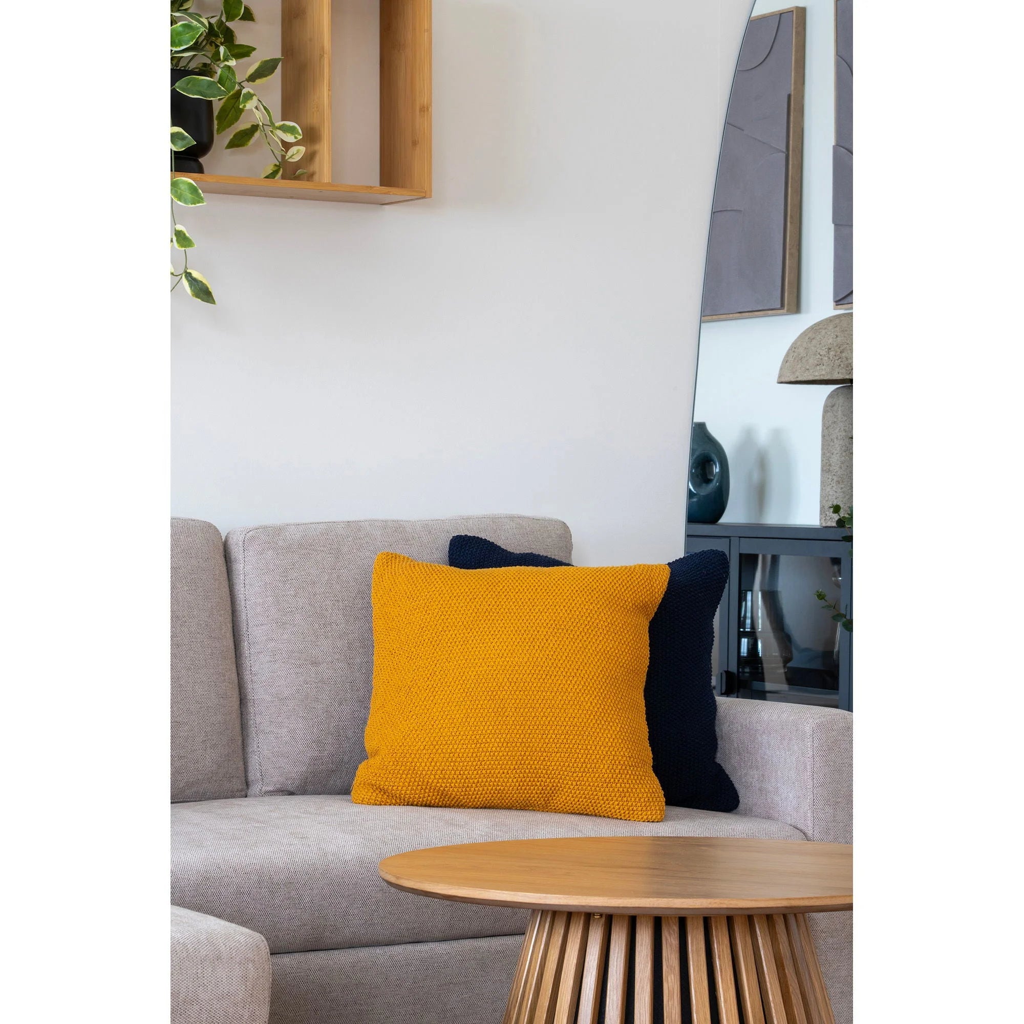 Coussin décoratif carré ocre texturé en coton recyclé sur canapé gris