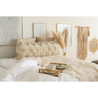 Coussin rectangulaire tufté en laine et coton écru avec motifs en relief sur lit douillet