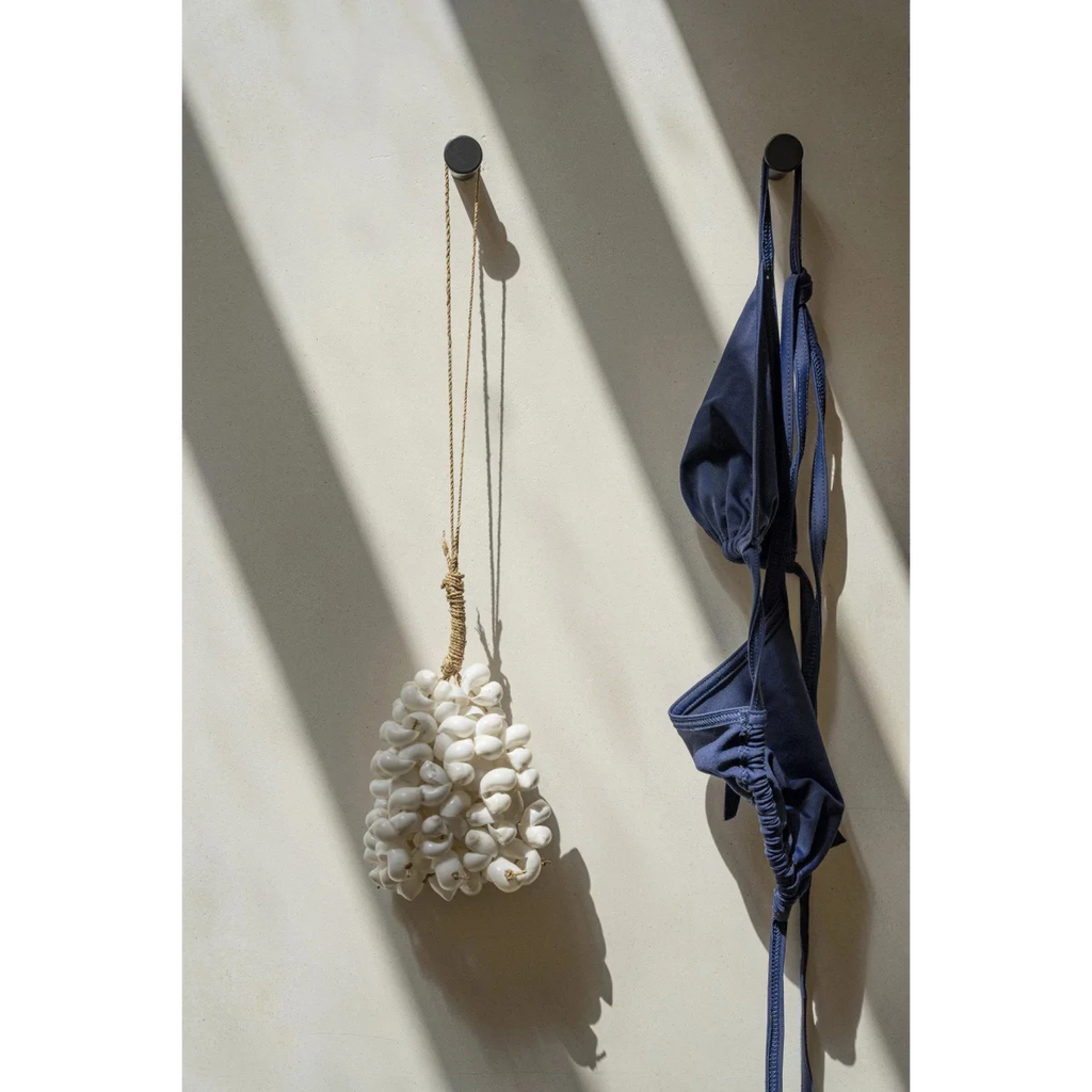 Maillot de bain deux pièces bleu marine suspendu sur un crochet mural en coquillages blancs