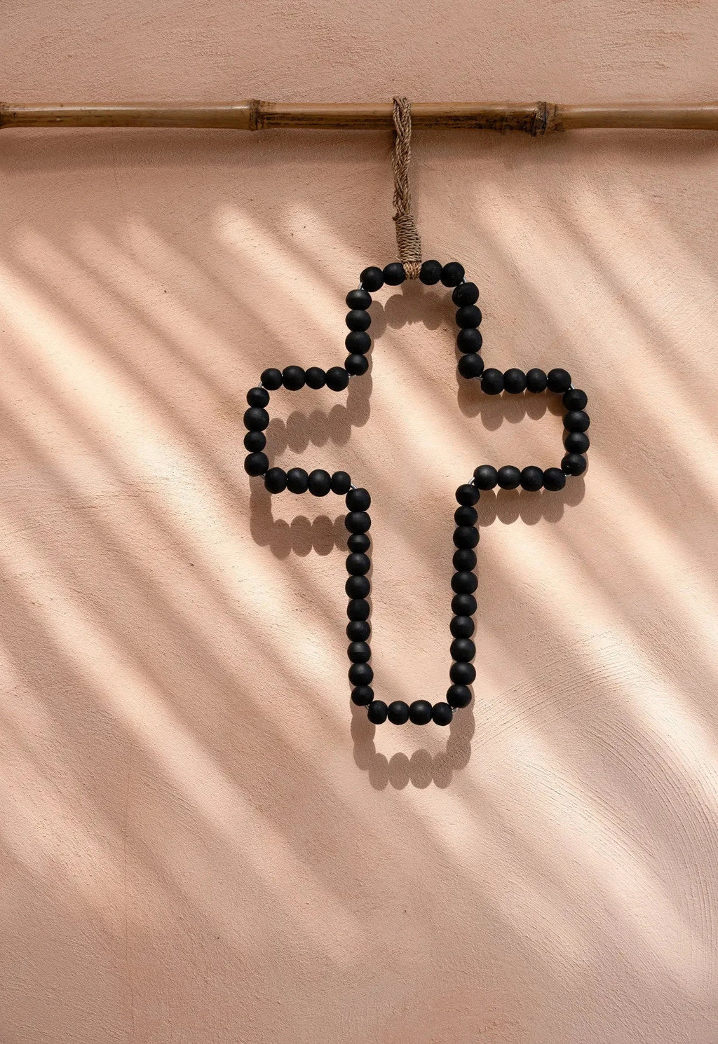 Nœud de corde tressée tan avec perles noires mates sur croix murale noire