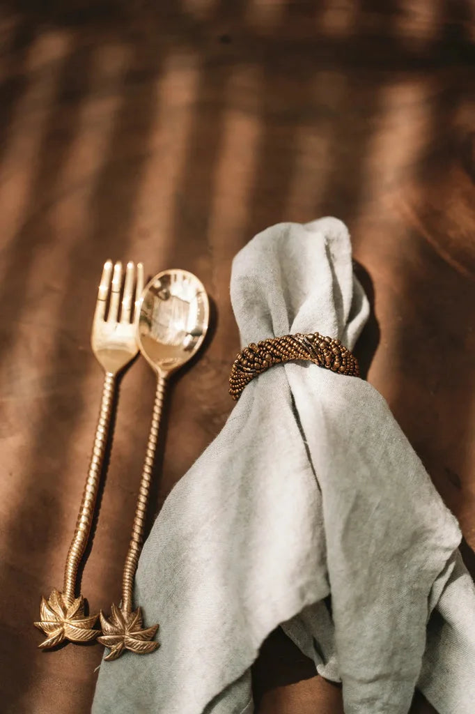 Couverts en argent avec manche en palmier doré et napkin en lin avec bague perlée