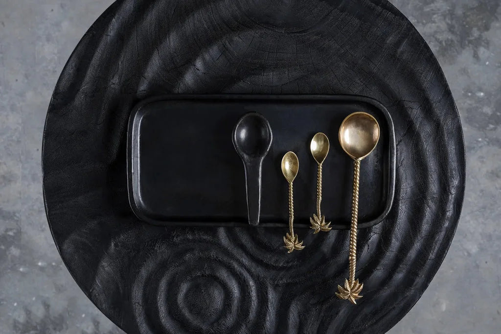 Plateau noir avec des cuillères décoratives en forme de palmier or pour salade