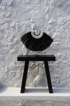 Collier à franges noires sur un support, décoration en herbe d’alang et coquillages