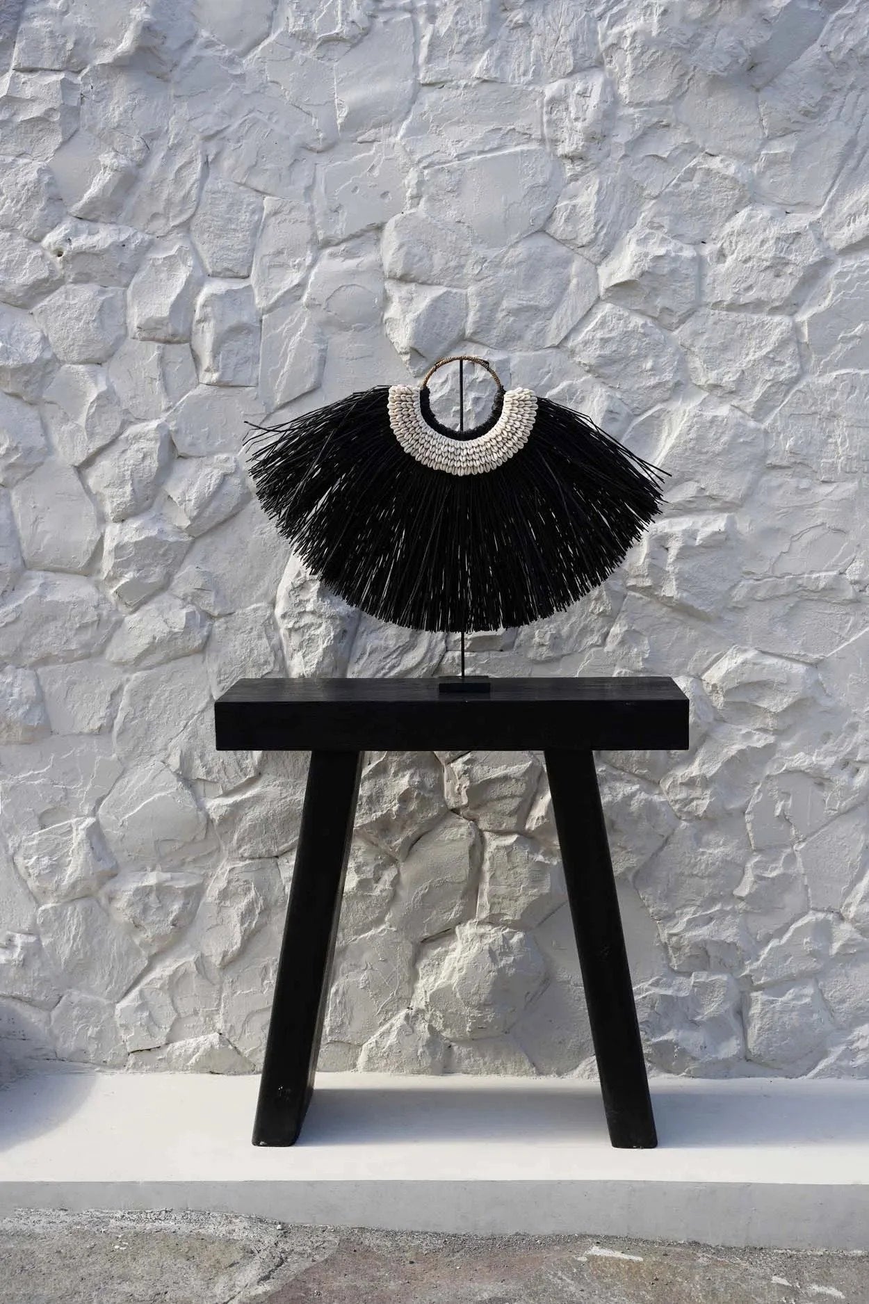 Collier à franges noires sur un support, décoration en herbe d’alang et coquillages