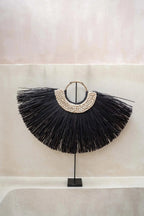Décoration murale en raffia noir et coquillages sur pied en forme d’arc