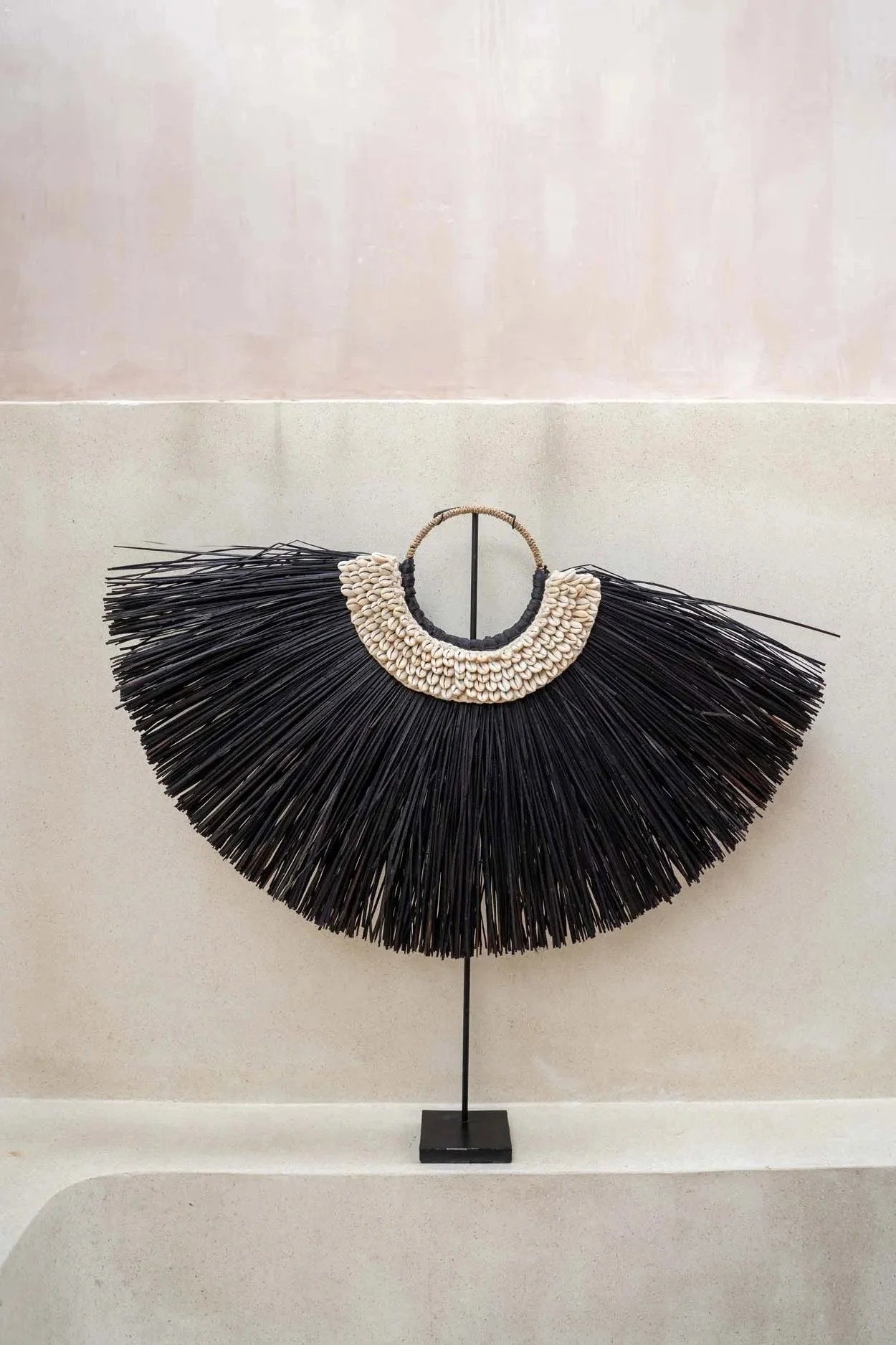 Décoration murale en raffia noir et coquillages sur pied en forme d’arc