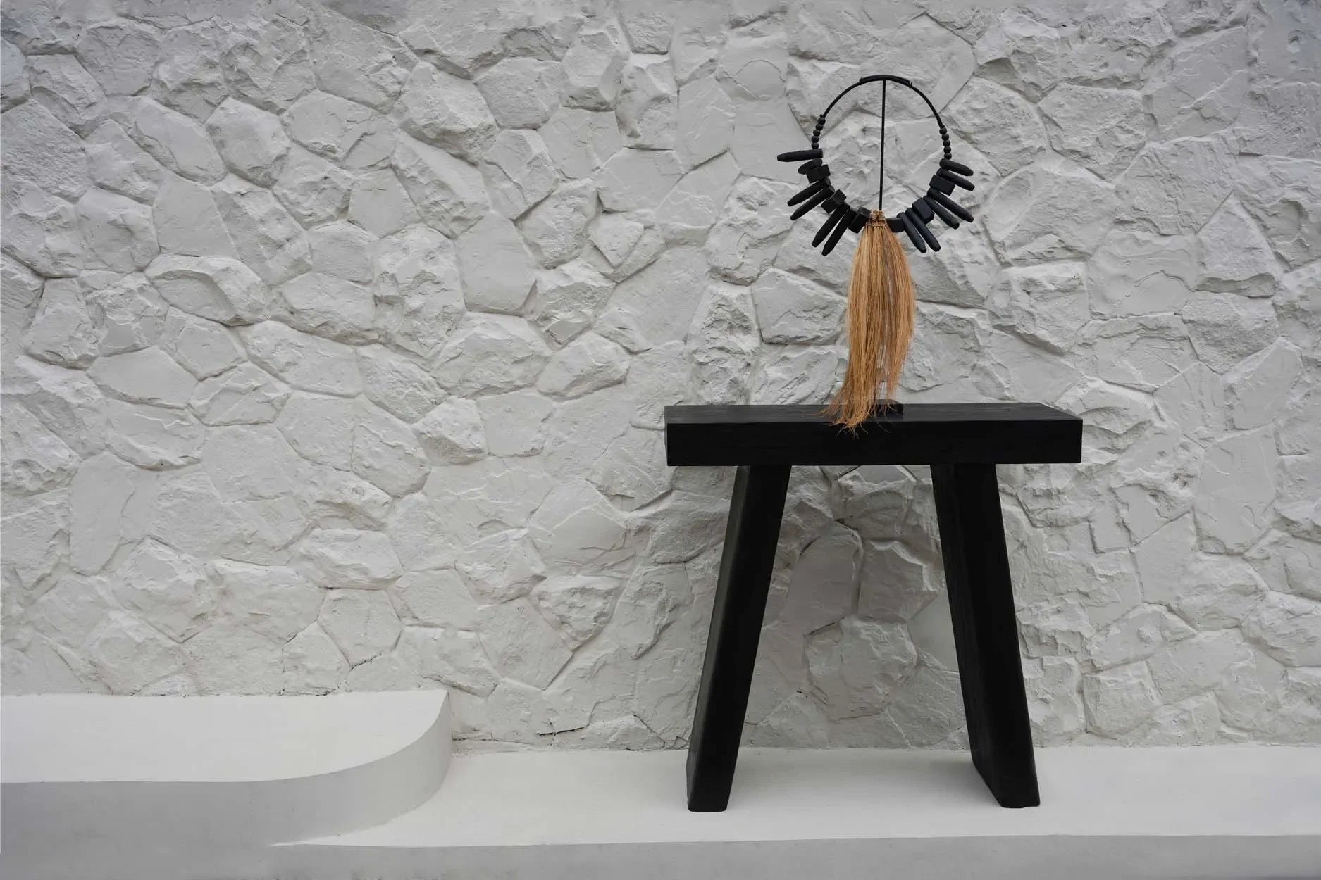 Haut-de-form noir avec frange en paille sur support décoration en herbe rayung et bois naturel
