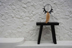 Tabouret minimaliste noir avec collier décoratif en éléments noirs et franges naturelles