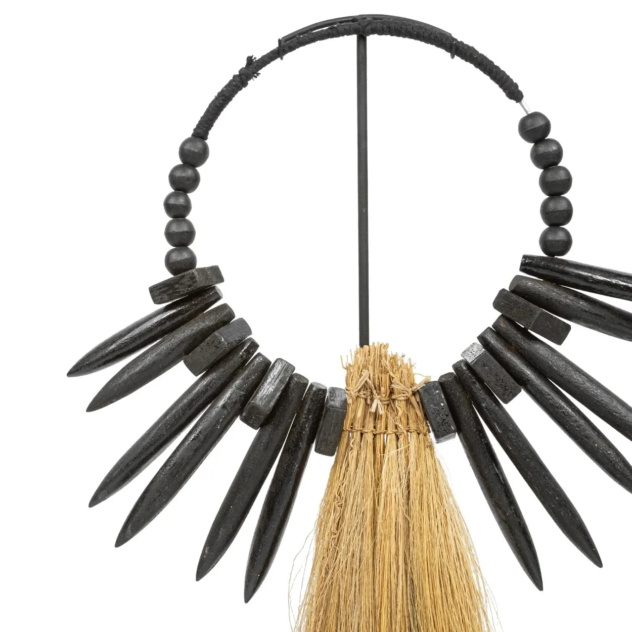 Collier en perles noires avec piques et tassel en paille sur support décoratif naturel