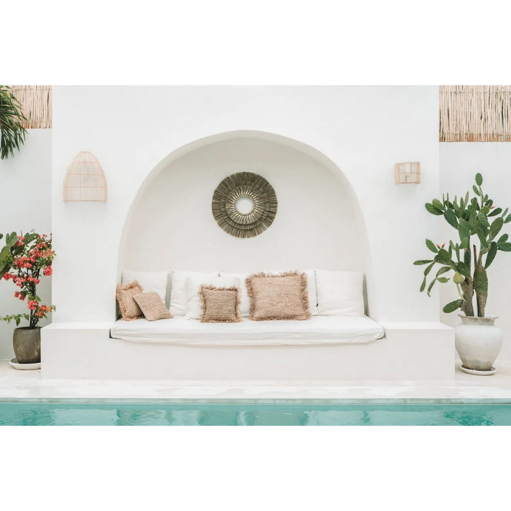 Lounge extérieur blanc avec coussins dans une alcôve en bord de piscine