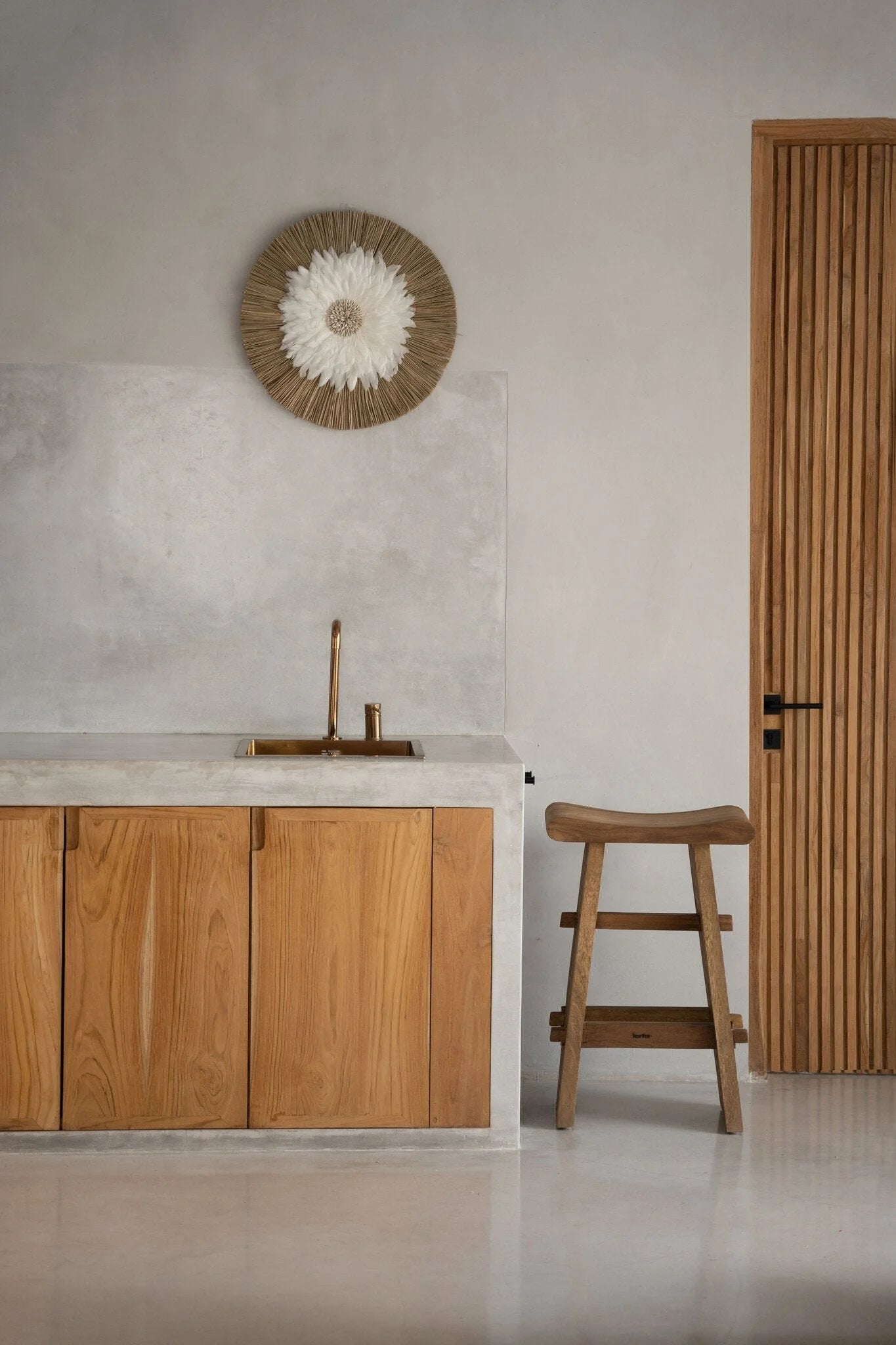 Décoration murale ronde en plumes blanches et coquillages naturels dans une cuisine minimaliste
