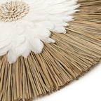 Décoration murale ronde en plumes blanches et coquillages naturels sur un mur