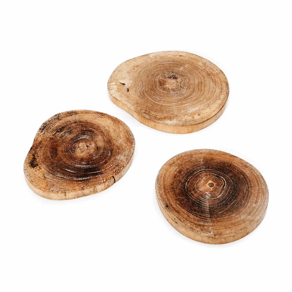 Trois sous-verres en bois en forme de tranches d’arbre.