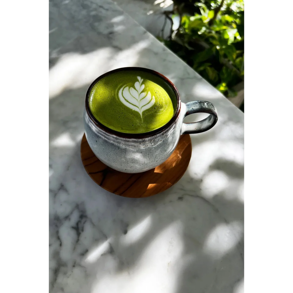 Matcha latte vert vif avec art latte blanc dans une tasse en céramique rustique