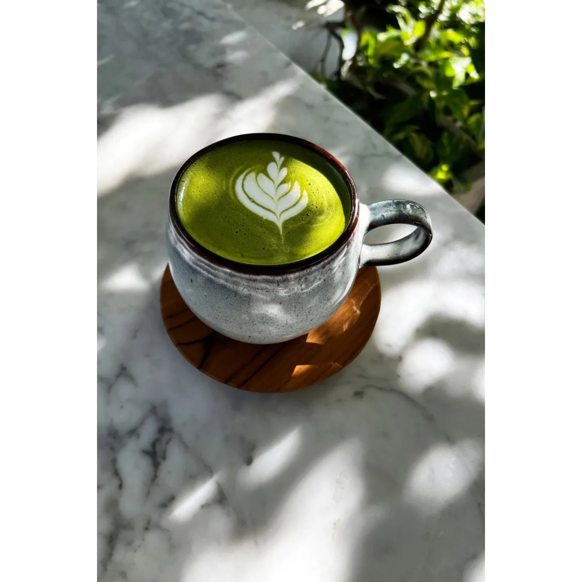 Matcha latte vert vif avec art latte blanc dans une tasse en céramique rustique