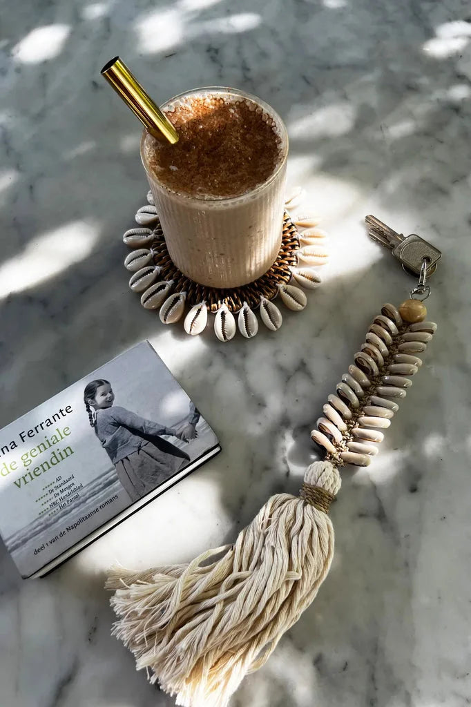 Iced coffee avec paille dorée sur le dessous de verre colonial en coquillage marron naturel