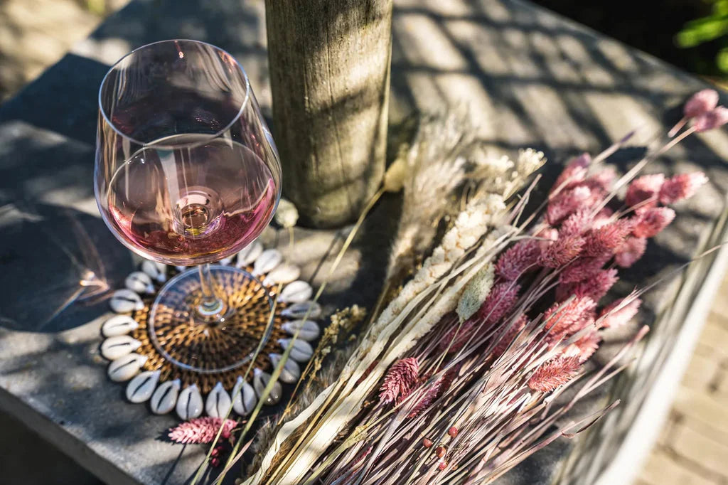 Verre de vin rosé avec le dessous de verre colonial en coquillage marron naturel