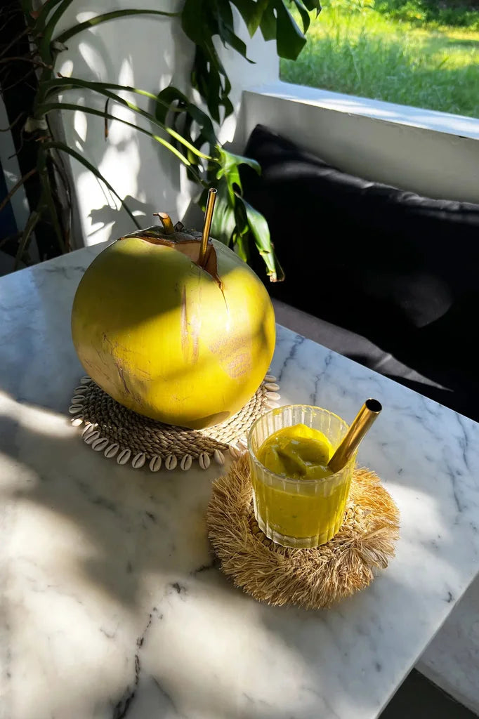 Verre de noix de coco jaune avec paille, en dessous de verre en coquillage d herbe marine naturel