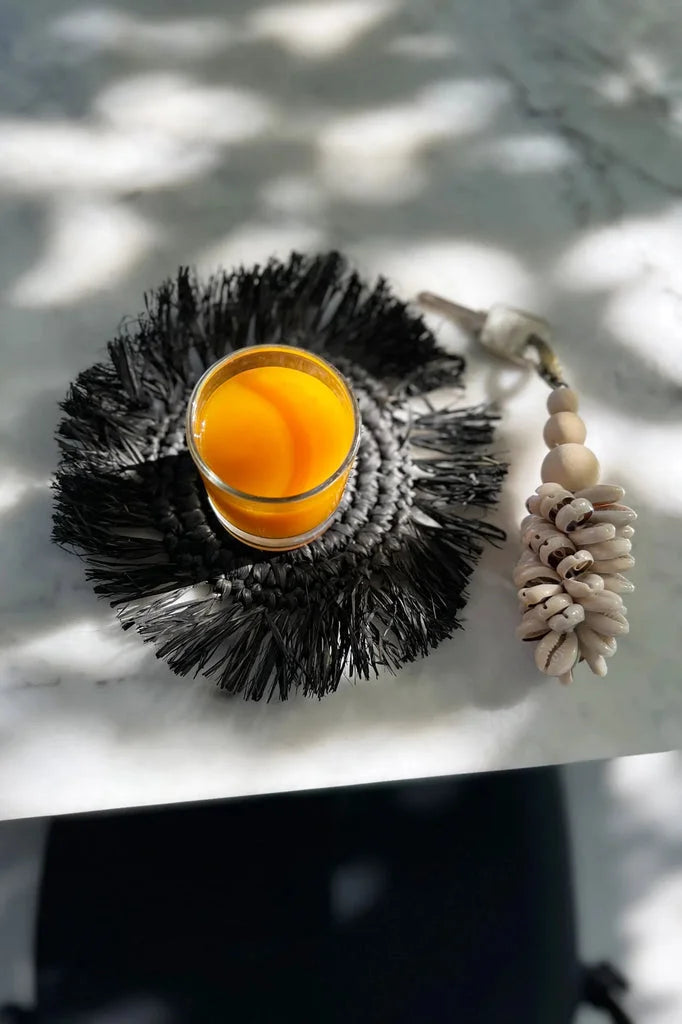 Verre orange sur dessous de verre en raphia noir à franges avec tassel décoratif