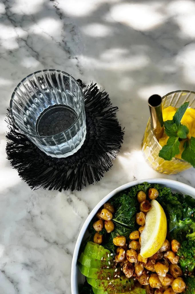 Salade saine dans un dessous de verre en raphia à franges noir moderne