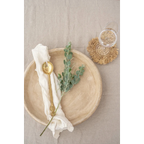 Assiette céramique beige avec cuillère dorée et branche d’eucalyptus verte