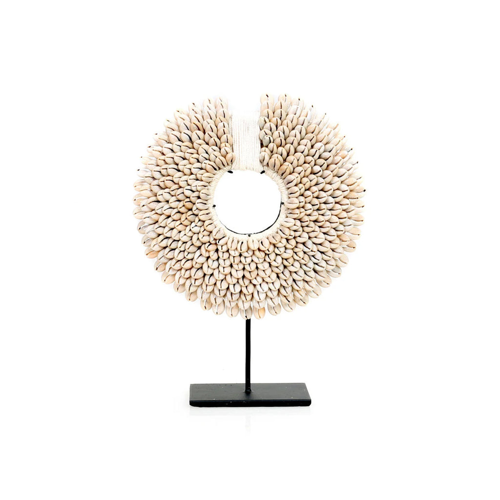 Un collier décoratif en cauris sur un support noir.