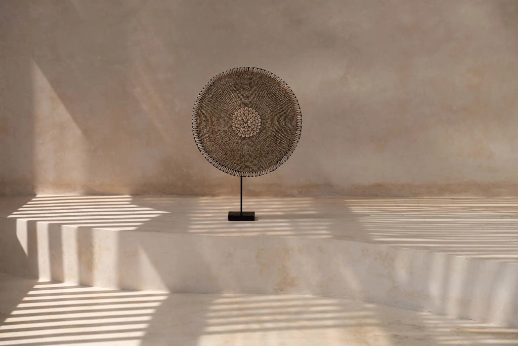 Disque décoratif en coquillages et perles sur socle noir texturé