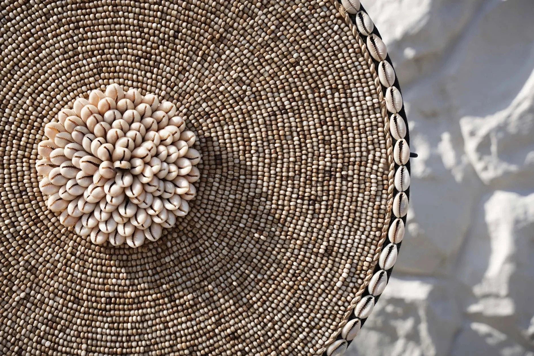 Disque décoratif en coquillages blancs et perles beige sur socle noir