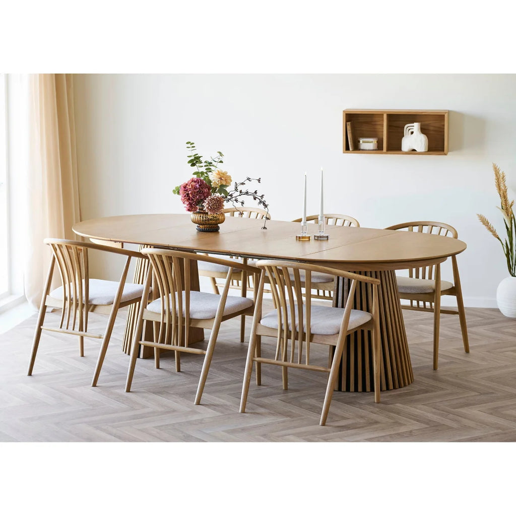 Table ovale en bois clair avec base cannelée et chaises rembourrées blanches