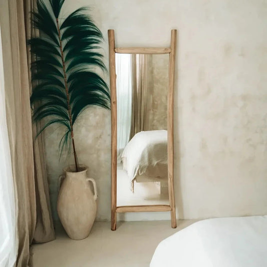 Miroir en teck dans une chambre avec un décor bohème et un lit en fond