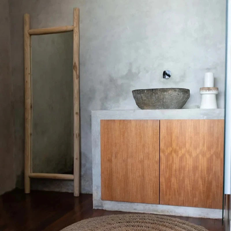 Grand miroir en teck posé dans une salle de bain minimaliste et naturelle