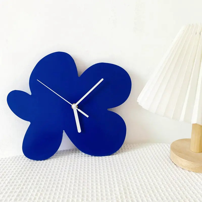 Horloge fleur abstraite bleue posée sur une table blanche, style épuré.
