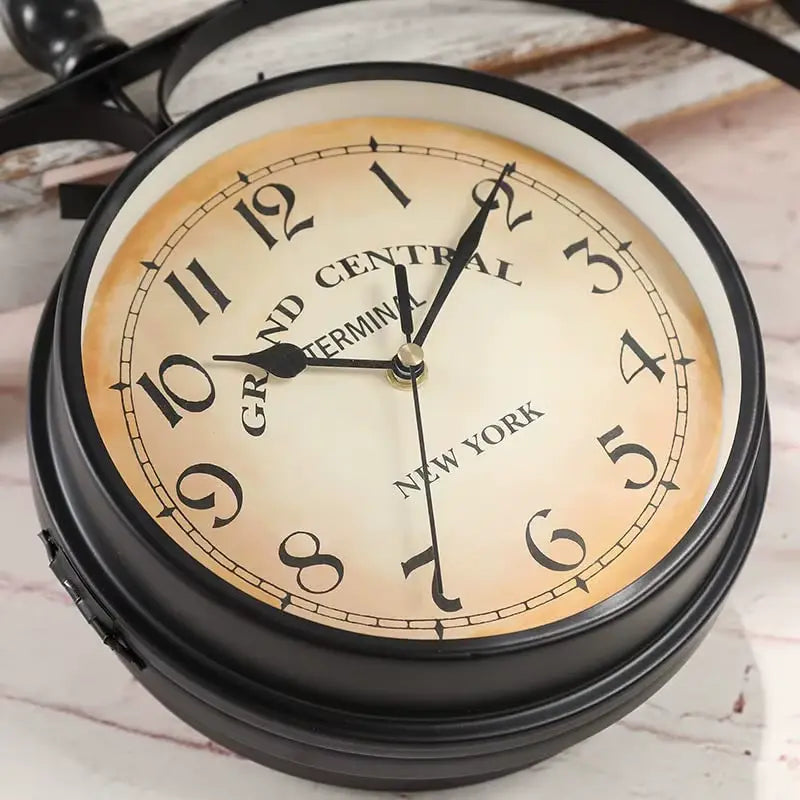 Gros plan sur l’horloge murale double face vintage avec support en fer forgé et cadran en verre