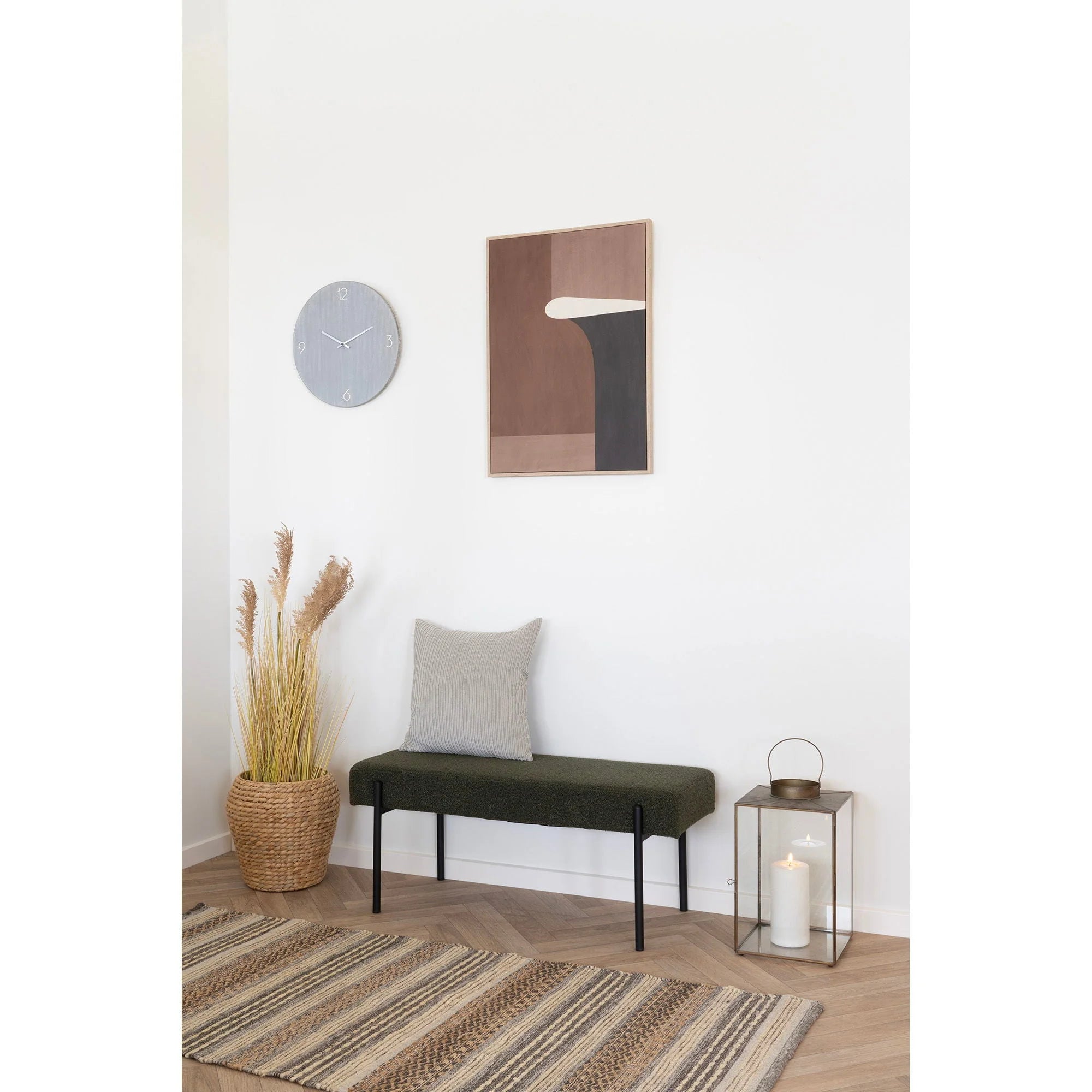 Banquette en tissu vert avec pieds noirs en dessous d une Horloge murale ronde MDF gris clair
