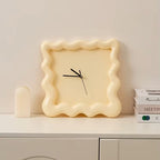Horloge ondulée couleur crème posée sur un meuble, style épuré.