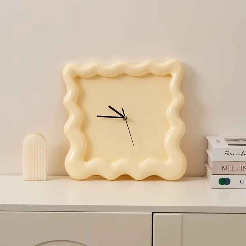 Horloge ondulée couleur crème posée sur un meuble, style épuré.