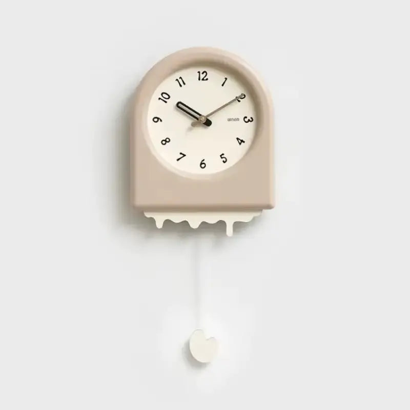 Horloge à pendule moderne beige avec un effet fonte suspendue sur un mur blanc dans un intérieur épuré.