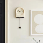 Horloge à pendule moderne accrochée sur un mur blanc dans une ambiance contemporaine et épurée.
