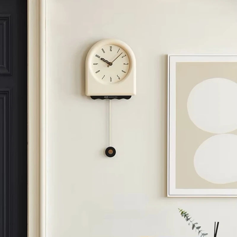 Horloge à pendule moderne accrochée sur un mur blanc dans une ambiance contemporaine et épurée.
