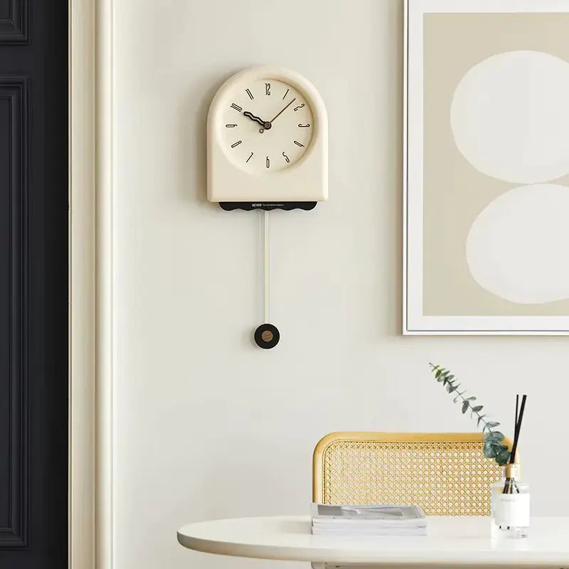 Horloge à pendule moderne crème accrochée sur un mur dans un intérieur décoré avec des éléments minimalistes.